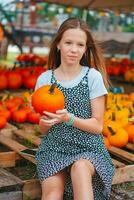 Beautiful little girl with pumpkins enjoying autumn day on the terrace. Happy Halloween photo