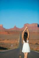 contento joven mujer en el famoso la carretera a Monumento Valle en Utah en su viaje en famoso cañón en EE.UU. increíble ver de el Monumento valle. foto