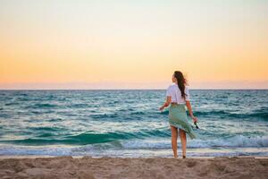 Young happy woman on the beach at sunset enjoy her sky view photo