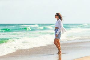 Young beautiful woman on beach vacation walking by the sea photo