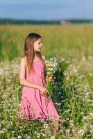 Portrait of girl in dress and straw hat on a chamomile field in summer photo