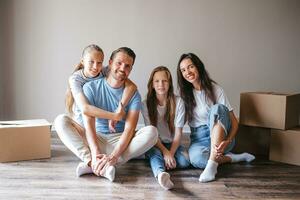 Happy family with two daughters with cardboard boxes in new house at moving day photo