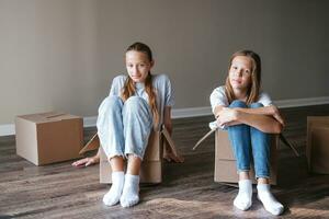 Young teen girls moving in new house with cardboard boxes photo