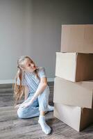 Happy adorable girl with cardboard boxes in new house at moving day photo