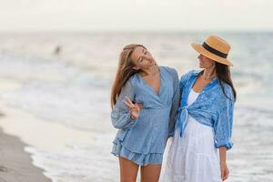 Beautiful mother and daughter at the beach enjoying summer vacation photo