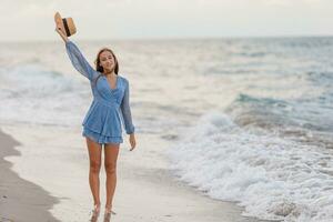 Beautiful teenager girl on tropical seashore walking at shallow water and having fun photo