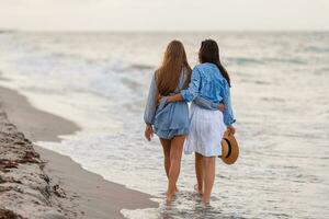 Beautiful mother and daughter at the beach enjoying summer vacation photo