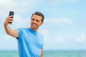 joven tomando selfie mientras camina en la playa foto