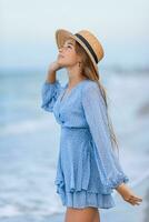 Beautiful teenager girl on tropical seashore at sunset. Beautiful little girl in dress at beach having fun. Happy girl enjoy summer vacation background the blue sky and turquoise water in the sea photo