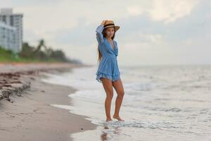 hermosa adolescente niña en tropical costa caminando a superficial agua y teniendo divertido foto