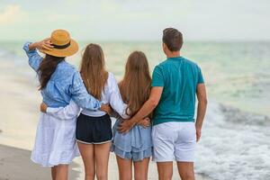Family of four have fun together on beach vacation at sunset photo