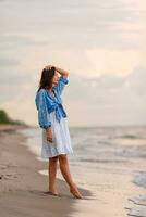 mujer feliz disfrutando de la hermosa puesta de sol en la playa foto