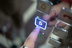 Man hand pressing button of elevator to fifth floor. photo