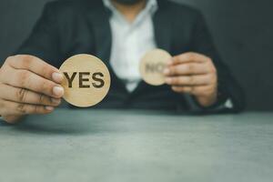 Businessman hand making a choice of Yes from between two cubes with Yes and No. Voting yes. photo