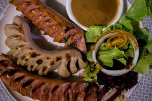 Three assorted grilled sausages on a white plate served with salad. Appetizing beer snacks set. photo