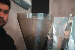 Asian man barista preparation pouring coffee bean into grind coffee in coffee shop. photo