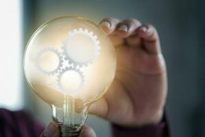 Glowing glass lightbulb with multiple gears inside photo