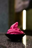 Soft serve strawberry ice cream swirl in black bowl photo