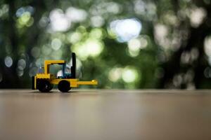 Yellow toy forklift loader on nature background with copy space for text. Logistics and industrial concept. photo