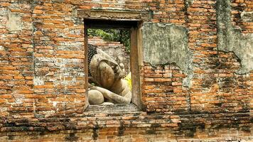 A perspective  of a reclining Buddha through a window with an old brick building, Ayutthaya, Thailand photo