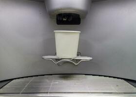 un papel café taza es metido en el lavabo de un automático café máquina. foto