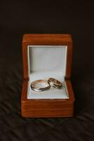 Close-Up Of Wedding Rings In Box On Table. wedding rings. Two golden wedding rings in a wooden box on a soft pillow. photo