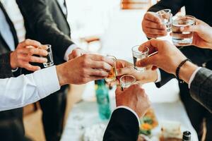 recortado ver de adulto hombre o mujer participación vino vaso. grupo de joven personas tintinamente cóctel bebida lentes tostado mejor amigos vistiendo un bajado cara máscara teniendo un gracioso reunión. foto