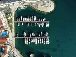 Aerial view of luxury sailing yachts and boats in yacht club near wooden piers. Top view of european city. Large boat parking near sea coast. Road to the lighthouse. Yachting in summer concept. photo