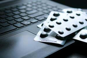 Antipyretic tablets in foil blister pack on a laptop keyboard selective focus photo