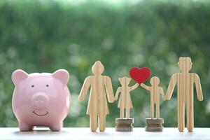 Model family with piggy bank and stack of coins money on natural green background,Save money for prepare in future and family finance concept photo