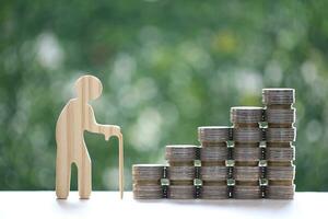 Retirement planning, Seniorman standing and stack of coins money on natural green background, Save money for prepare in future and pension retirement concept photo