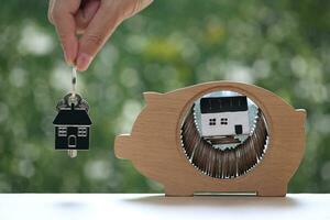 Model house in piggy bank on natural green background, Save money for prepare in future and real estate concept photo