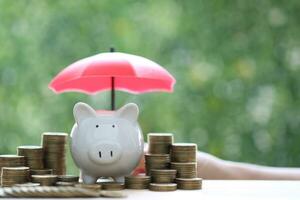 Piggy bank and stack of coins money on natural green background, Saving for prepare in future and Business investment concept photo