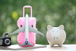 Saving planning for Travel budget of holiday concept, piggy bank and airplane on passport with natural green background photo