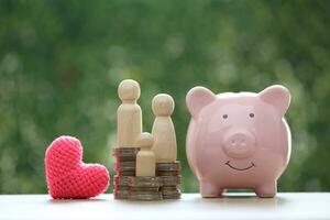 Model family with piggy bank and stack of coins money on natural green background,Save money for prepare in future and family finance concept photo