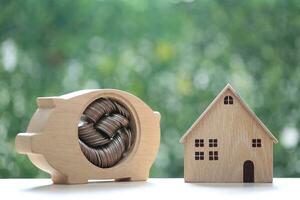 Finance, Model house with piggy bank and stack of coins money on natural green background,Business investment and real estate concept photo