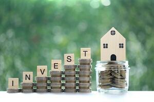 Mortgage,Model house and stack of coins money on natural green background,Business investment and real estate concept photo