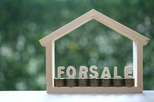 HOME FOR SALE,Model house and stack of coins money on natural green background,Business investment and real estate concept photo