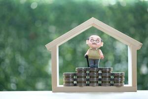 Retirement planning, Seniorman standing on stack of coins money on natural green background, Save money for prepare in future and pension retirement concept photo