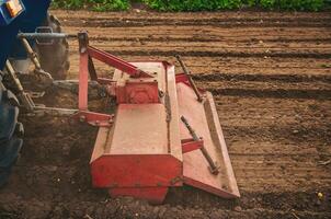 The tractor works the soil of the field by loosening and mixing it. Softening of the soil and destruction of the root system of the previous harvest. Land cultivation. Farming. photo