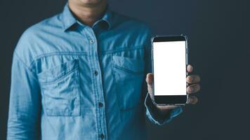 The left hand man showing a black smart phone or cellphone and a white screen display for mockup content at blue tone background. photo