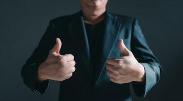 Portrait of businessman in suit standing thumbs up, half body and not showing face. photo