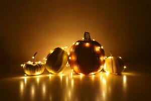 Four little pumpkins wrapped around a string lights garland on background highlighted yellow with shadows. Festive holidays Thanksgiving and Halloween decor concept. Place for text. photo