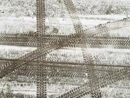 Different tires prints of the cars wheels crossing on road surface covered with thin layer of snow. Abstract asphalt horizontal background. photo