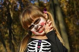 Portrait of little girl with sugar skull makeup. Spooky angry emotions on her face. Masquerade costume for Day of Dead, Dia de los Muertos. Halloween skeleton character, creepy zombie. photo