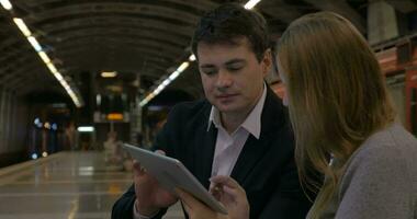 Man and woman passing time with touch pad in the underground video