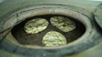 Indian cuisine tandoori roti making in original clay oven, Indian flat bread known as naan or roti nan, chapati at Indian restaurant close up scene with blur background. video