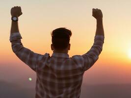 man raising his arms and raising his hand to the sun at the top of the mountain, sunrise. photo