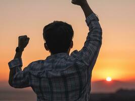 man raising his arms and raising his hand to the sun at the top of the mountain, sunrise. photo