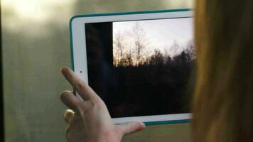 Woman with pad in the train making a video of passing landscape